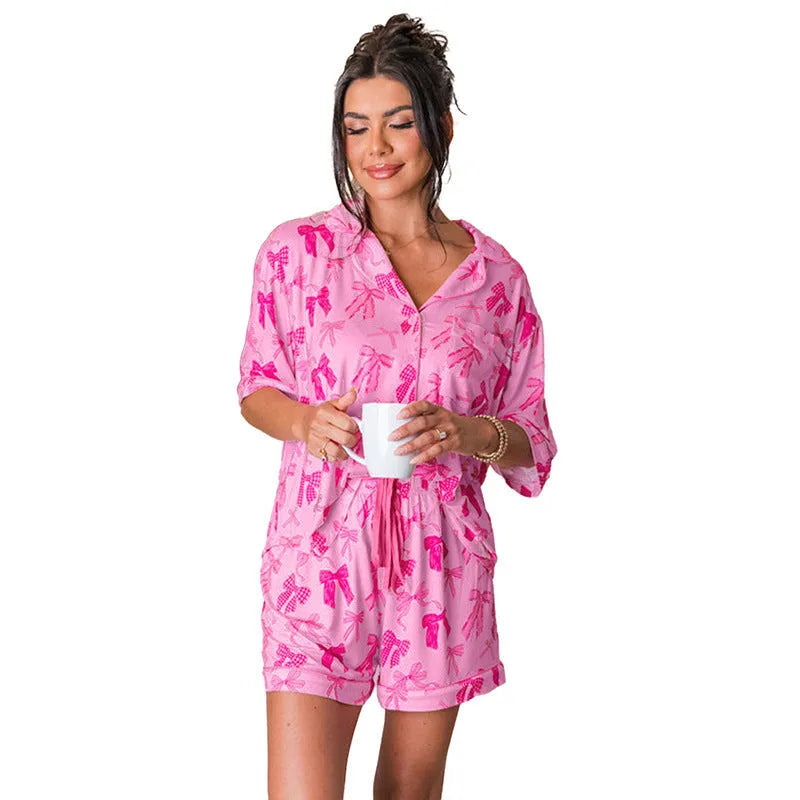 Pink women's two-piece pajama set with a bow print, made from lightweight polyester fabric.