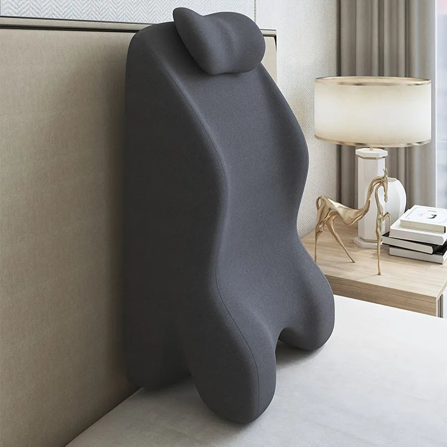 A prone position stomach sleeping pillow shown in a light grey colour, designed for use while reading in bed.