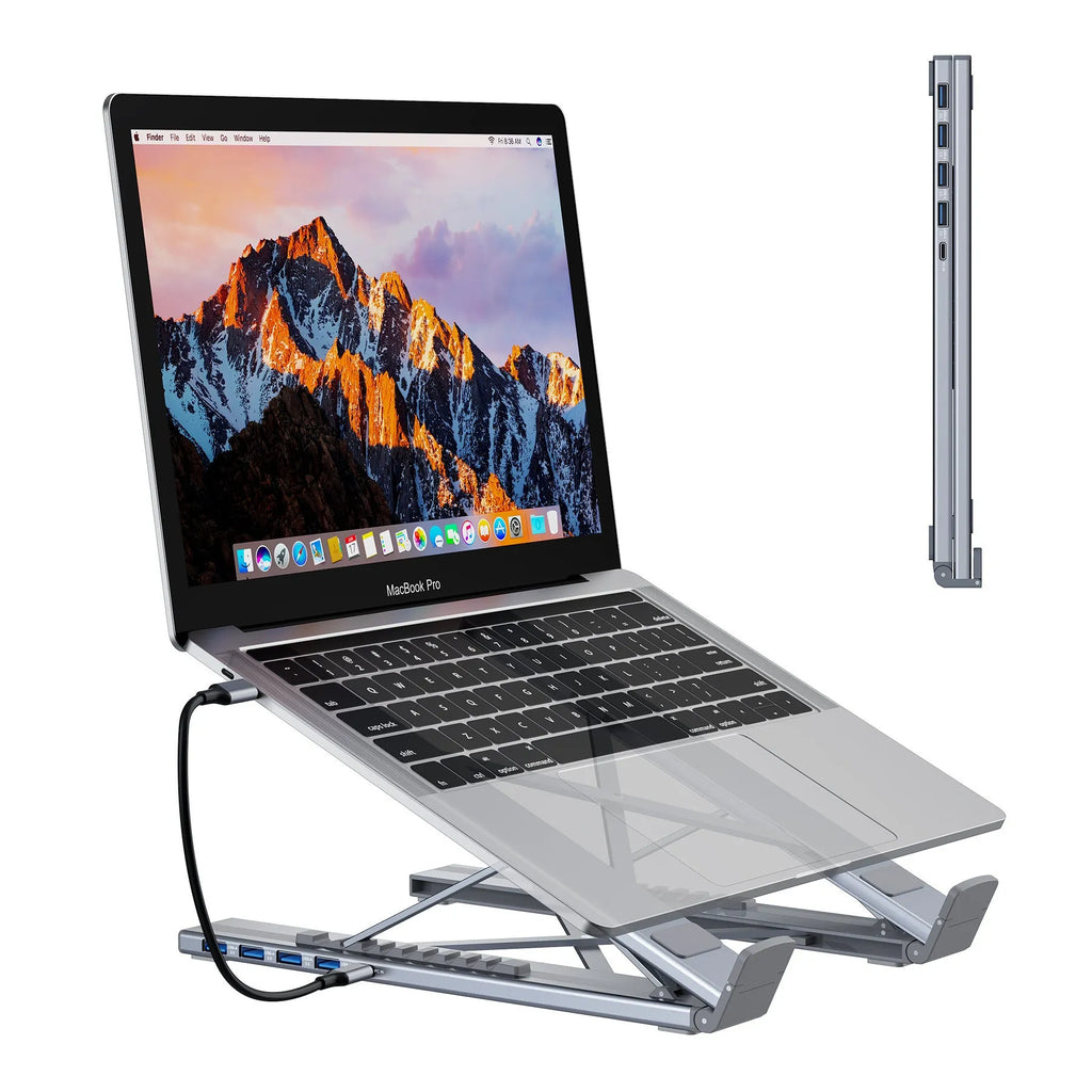 Aluminium folding laptop stand with built-in multi-port docking hub on a desk.