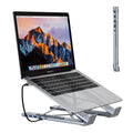 Aluminium folding laptop stand with built-in multi-port docking hub on a desk.