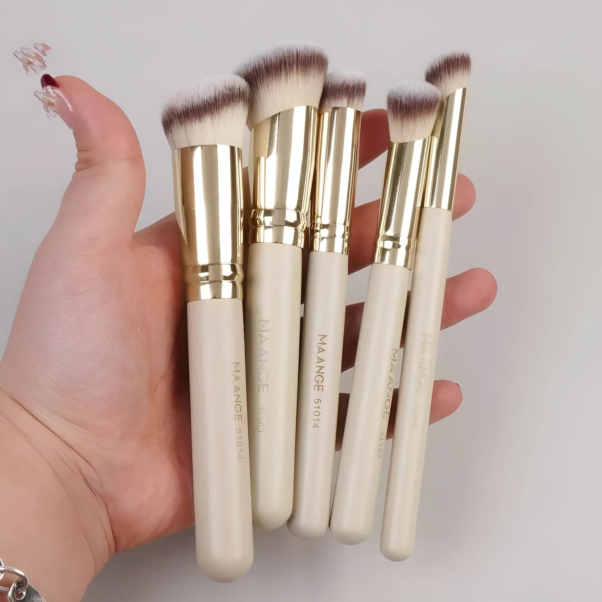 MAANGE set of five apricot-coloured makeup brushes with an angled blush brush on a grey background.