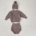 Dark brown knitted 3-piece set for infant girl with pullover blouse, pants, and fur ball hat