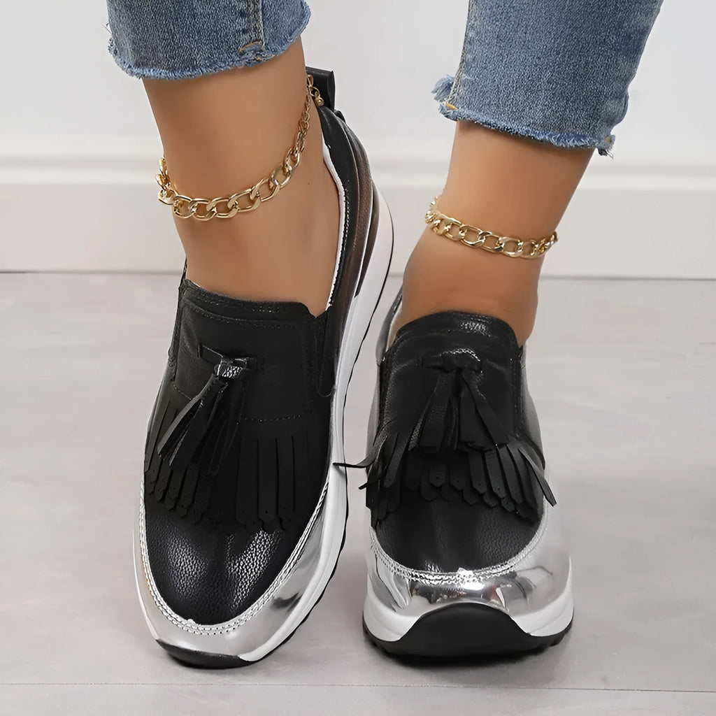 Women's black casual platform shoes with tassel detail and a low wedge heel on a white background.