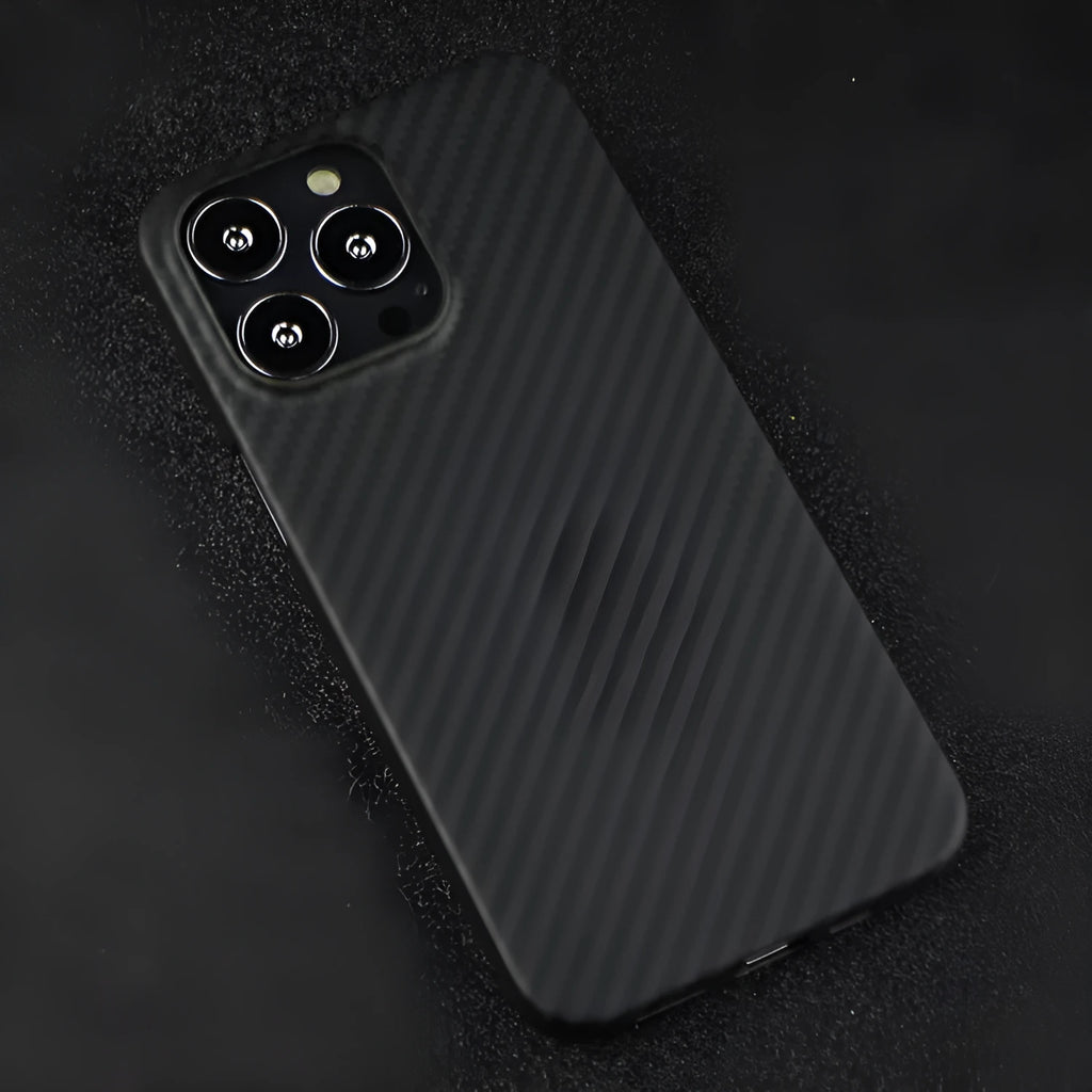 Dull black Kevlar iPhone case with volcanic crater texture next to a MagSafe charger.