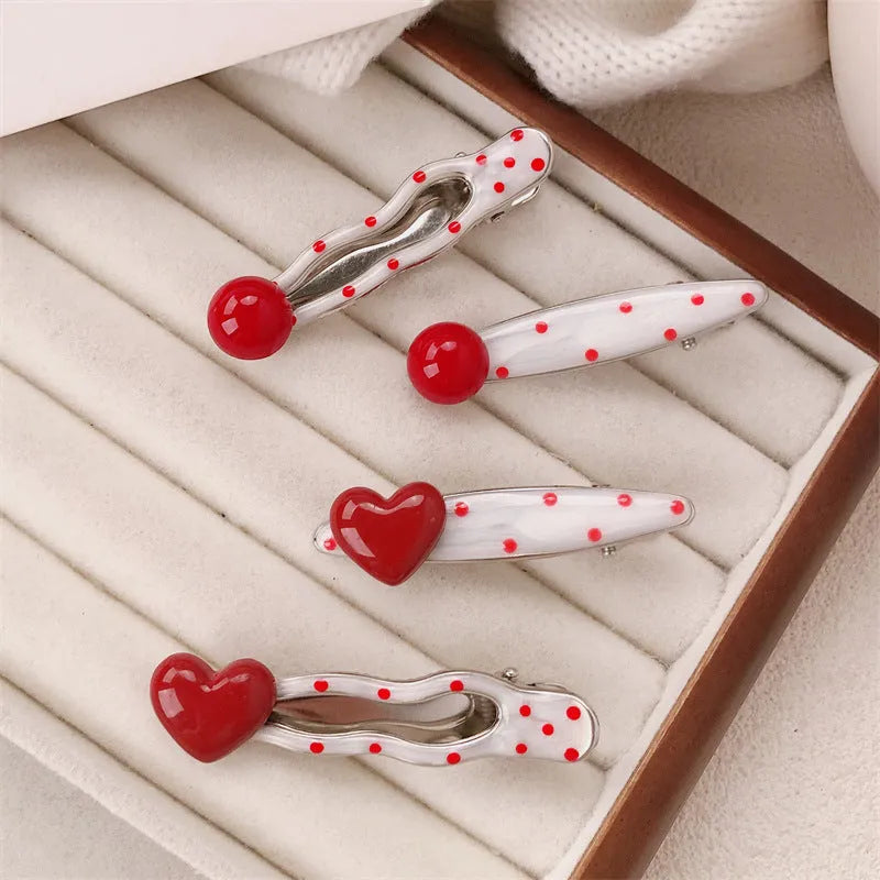 Red love heart-shaped hair clip with white polka dots and a green willow leaf decoration.