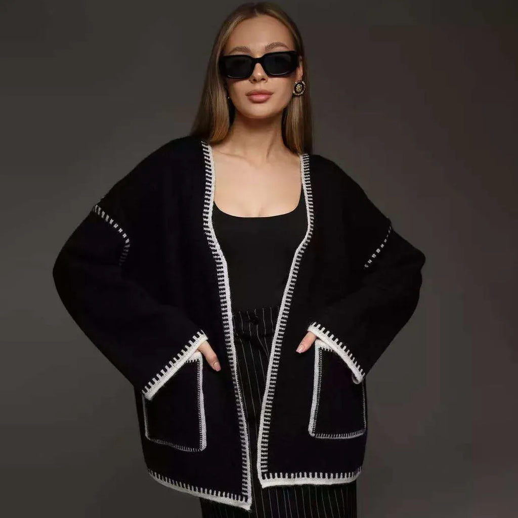 A white lace-up knitted cardigan with long sleeves on a hanger, showing the front tie detail.