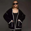 A white lace-up knitted cardigan with long sleeves on a hanger, showing the front tie detail.