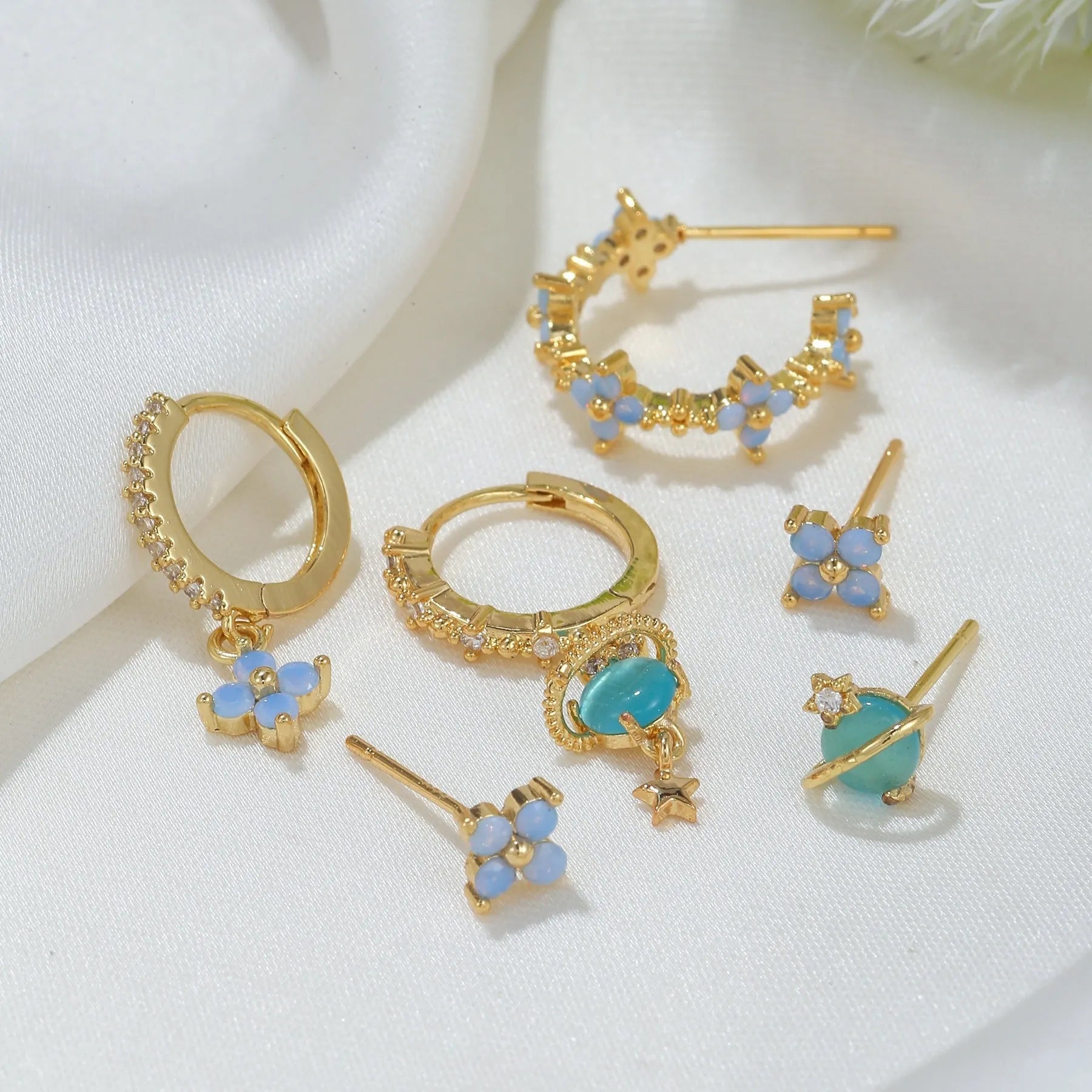 Gold and silver Japanese Korean style stud earrings with blue flower nail shape and zircon mosaic detail.