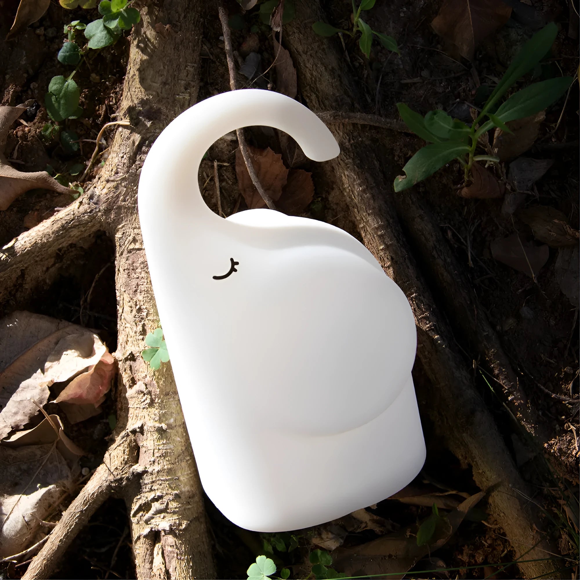 White elephant silicone night light with warm glow on a bedside table.