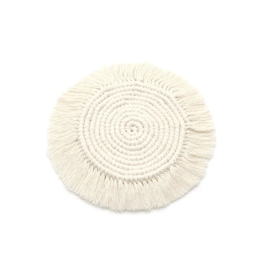 Hand-woven round beige cotton string coaster on a wooden table with a glass of water