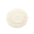 Hand-woven round beige cotton string coaster on a wooden table with a glass of water