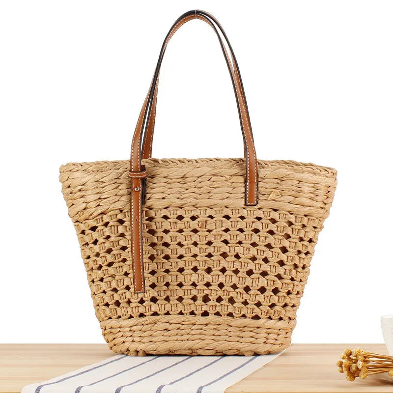 Beige paper-string woven shoulder bag with adjustable strap showing horizontal square design and straw elements