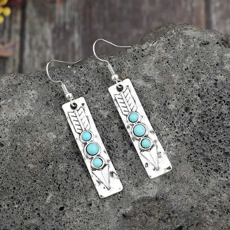 Long silver geometric drop earrings with blue turquoise stone inlays on a retro-style setting.