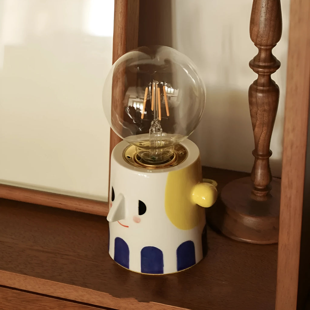 Handmade ceramic bedside lamp with a ball headlight design on a nightstand.