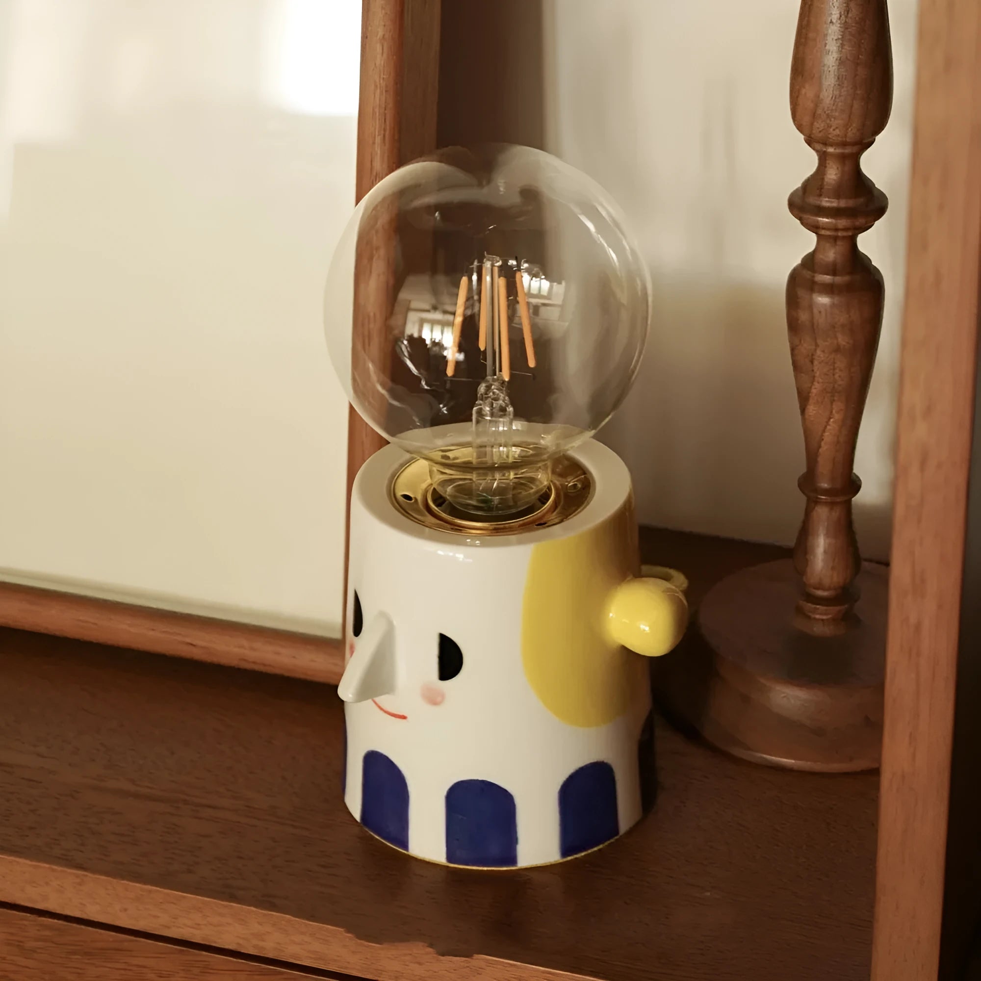 Handmade ceramic bedside lamp with a ball headlight design on a nightstand.