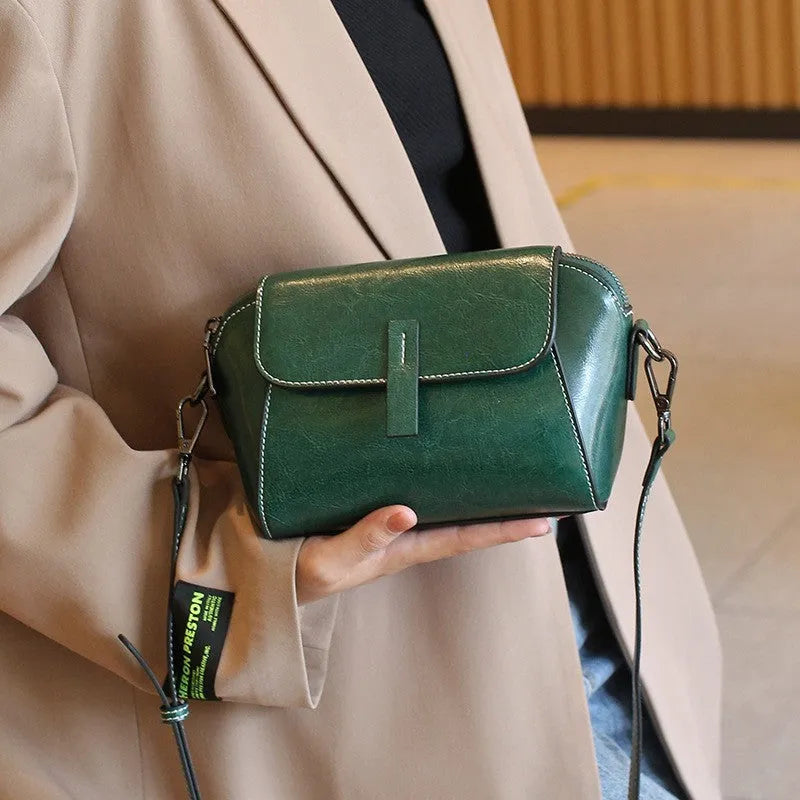Brown leather women's crossbody messenger bag showing shell shape and visible stitching.