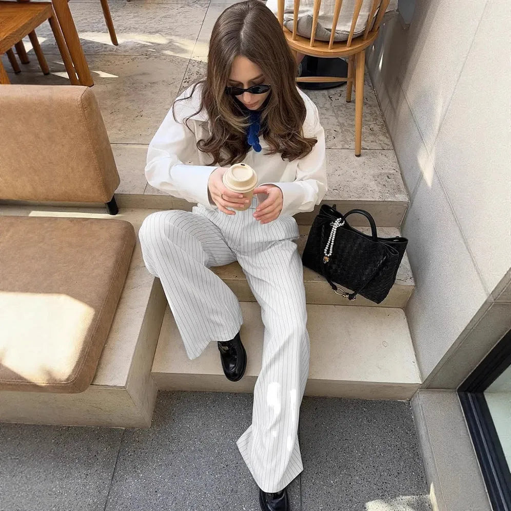 White wide-leg trousers with vertical stripes, featuring a loose casual fit and a front zipper fastening.