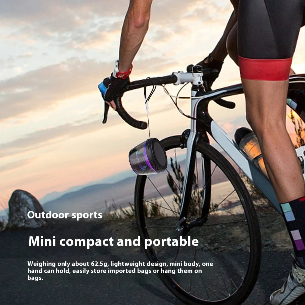 Small portable black Bluetooth speaker with coloured ambient light, shown with a magnetic base.