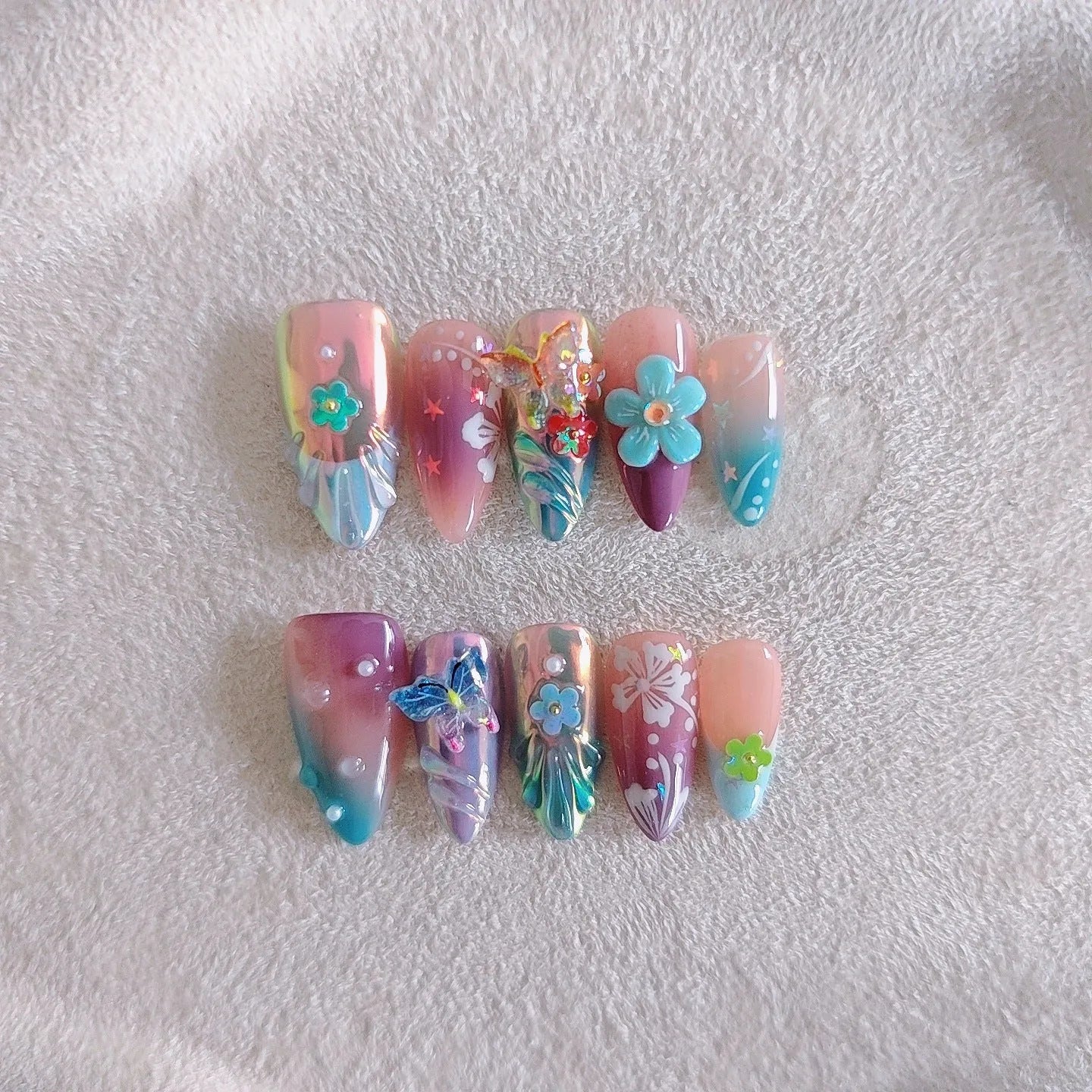 Handmade press-on false nails with embossed colourful small flowers and butterfly designs in almond shape.
