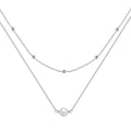 Close-up of a women's double layer sterling silver necklace with two round freshwater pearls on a geometric pendant.