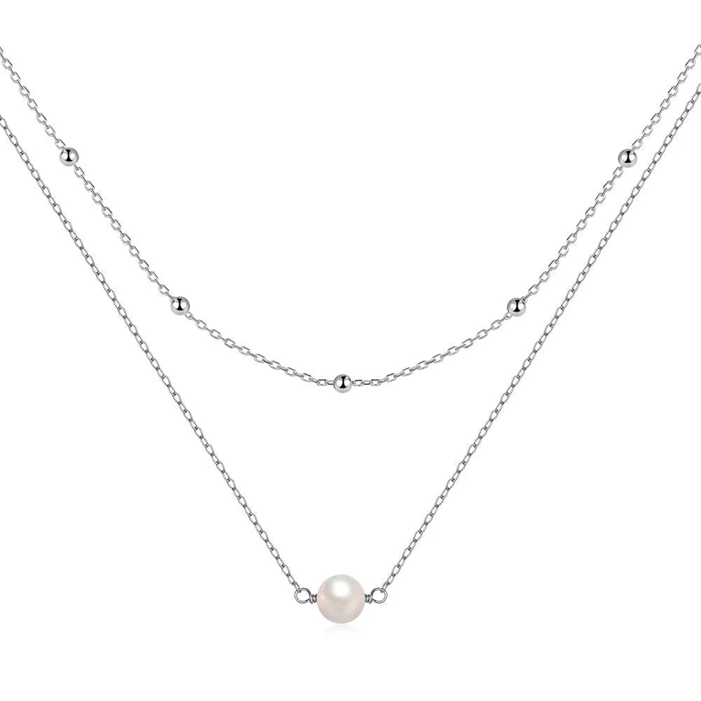 Close-up of a women's double layer sterling silver necklace with two round freshwater pearls on a geometric pendant.