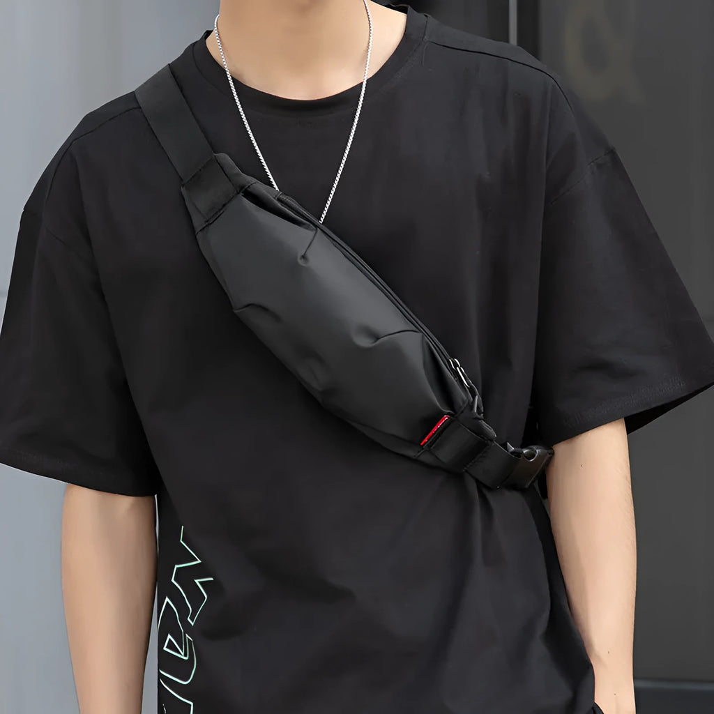 Black Oxford cloth men's crossbody waist pack showing front zipper and compact size.