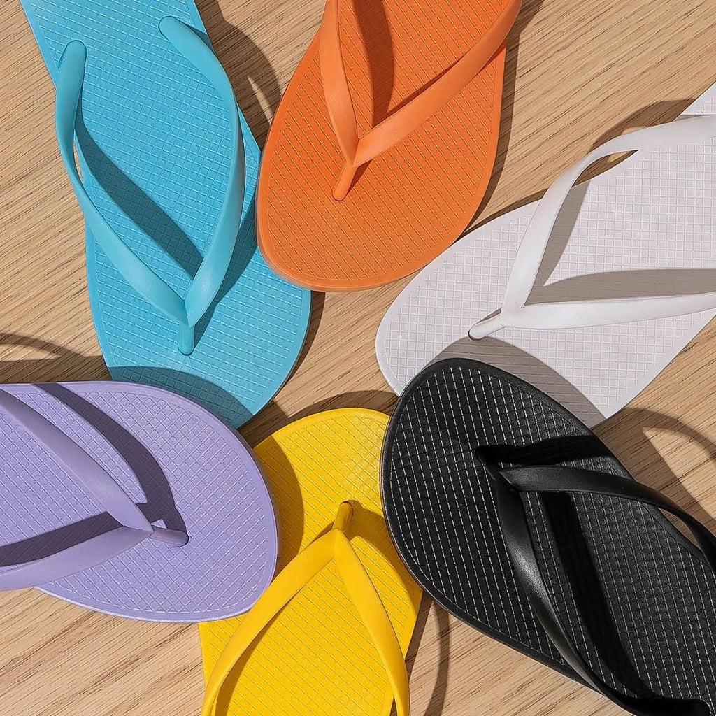 Orange foldable plastic beach slippers with non-slip patterned soles and hollow-out uppers.