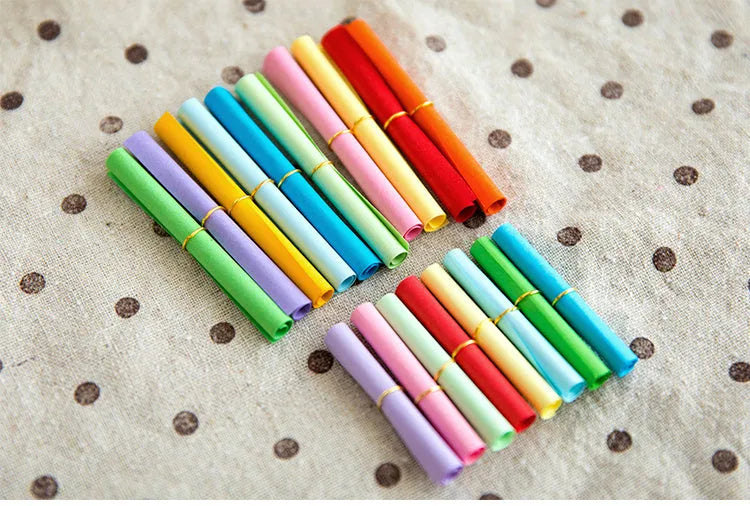 Assorted colourful mini paper scrolls with metal eyelets, shown in 3x7cm, 4x7cm and 5x5cm sizes