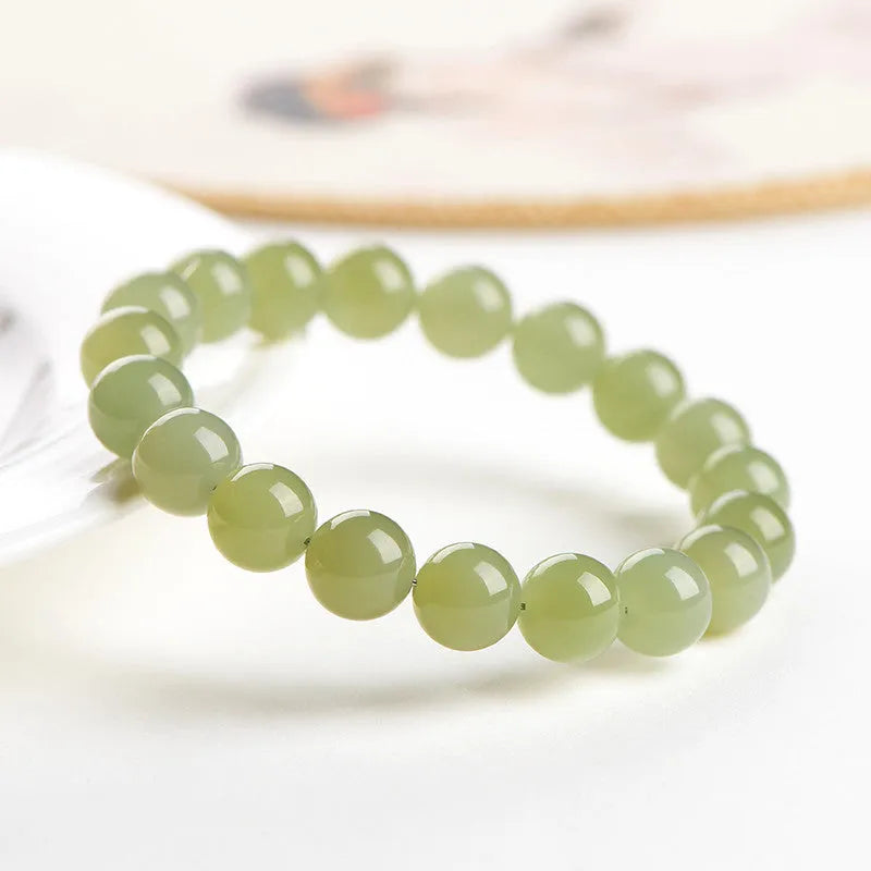 Polished Hetian jade ball bead bracelet in clear colour on wrist, showing spherical beads.