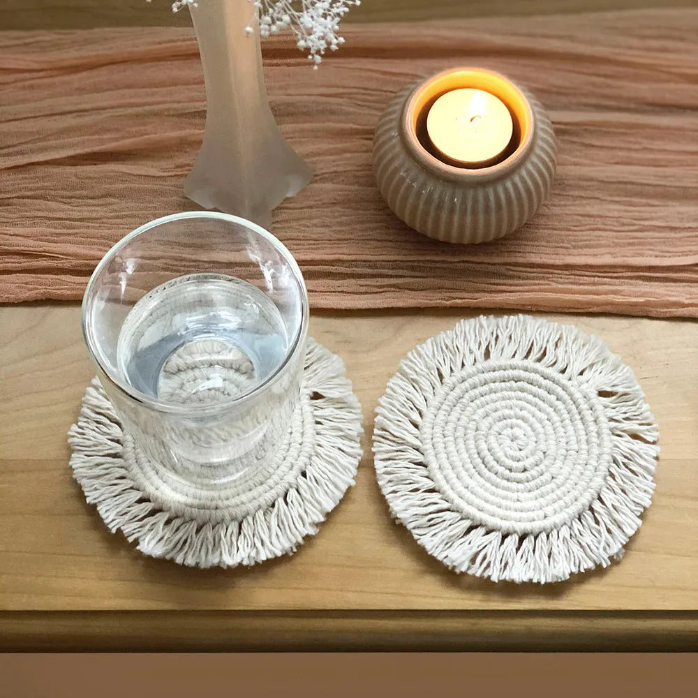 Hand-woven round beige cotton string coaster on a wooden table with a glass of water