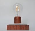 Magnetic levitating light bulb floating above an imitation wood base on a desk.