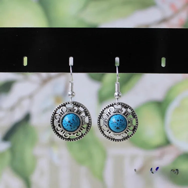 Handmade Miao ethnic style silver earrings with a blue turquoise flower disk and geometric patterns.