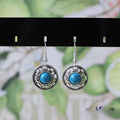 Handmade Miao ethnic style silver earrings with a blue turquoise flower disk and geometric patterns.
