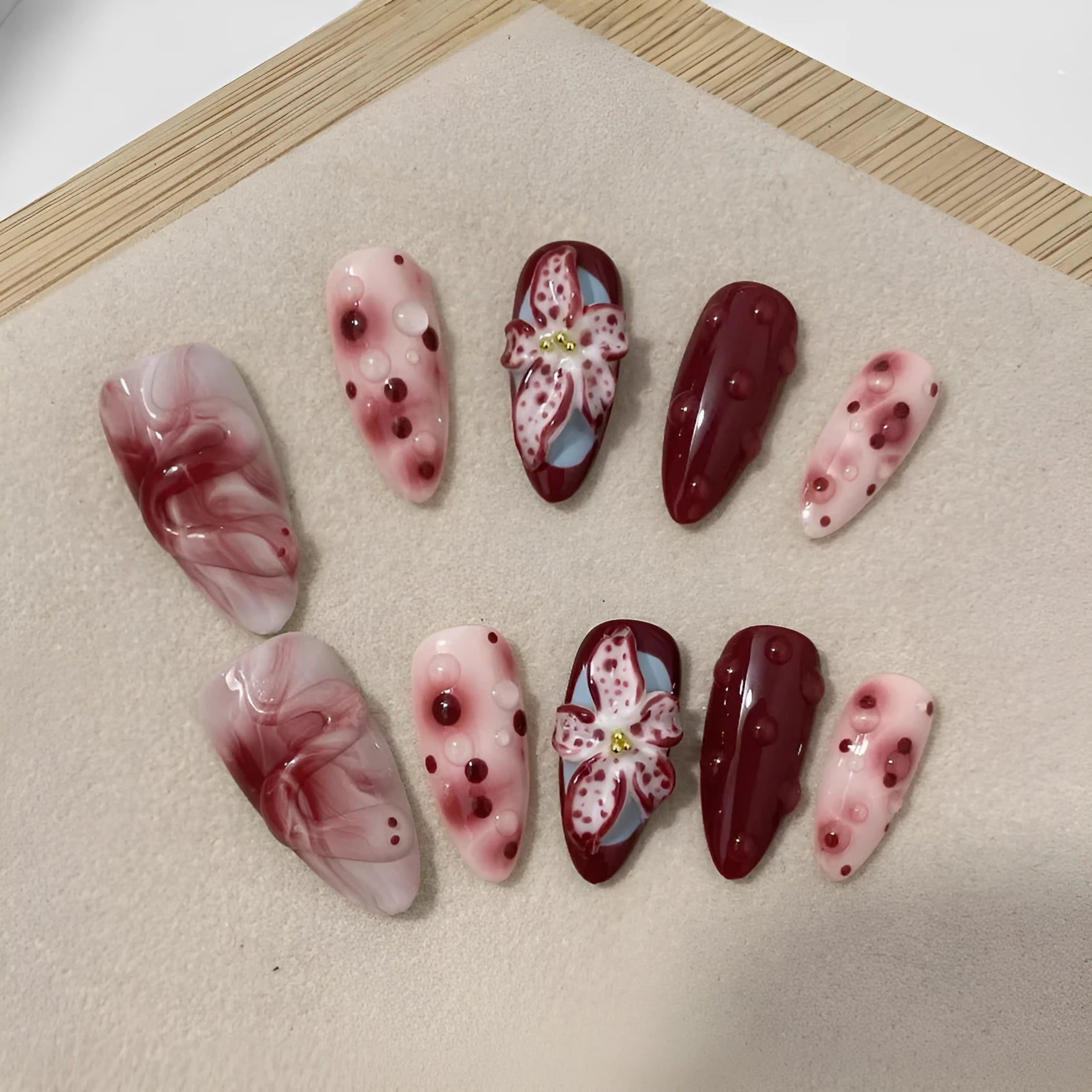Almond-coloured hand-painted artificial nails with 3D carved rose and butterfly designs, shown in short and almond shapes.