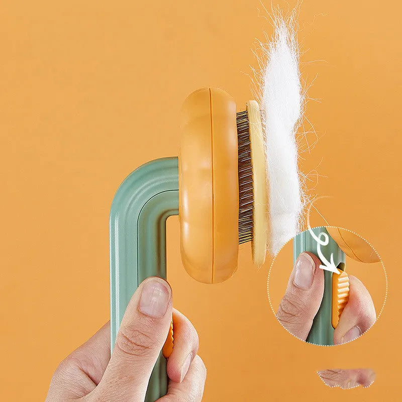 Hand holding a white and pumpkin coloured pet grooming brush with many stainless steel needles.