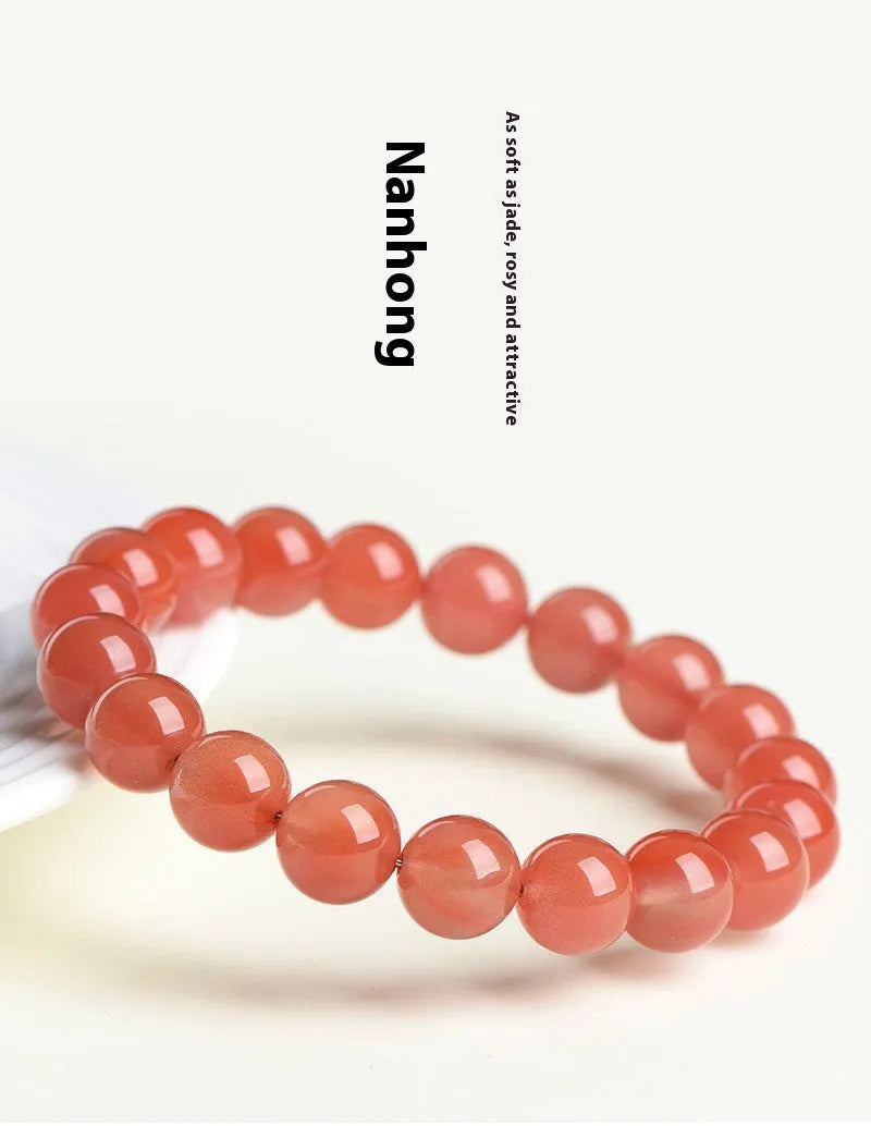 Natural cherry red agate bracelet with polished beads in a scattered design on a wrist.