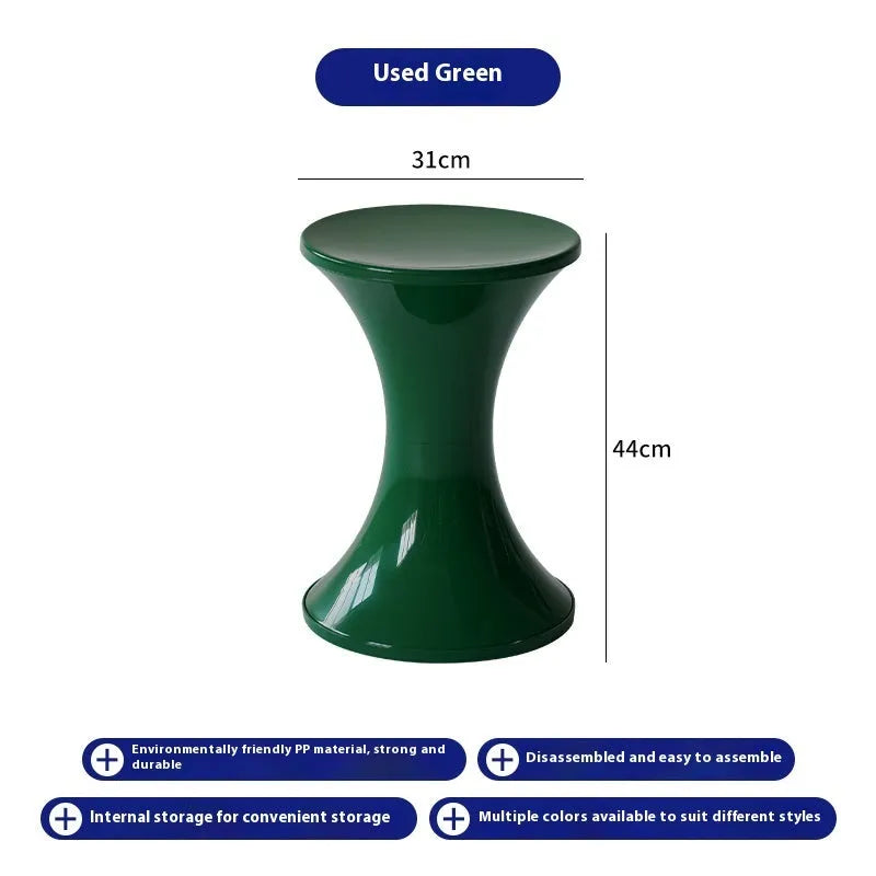 Green plastic hourglass-shaped shoe changing stool on a wooden floor.