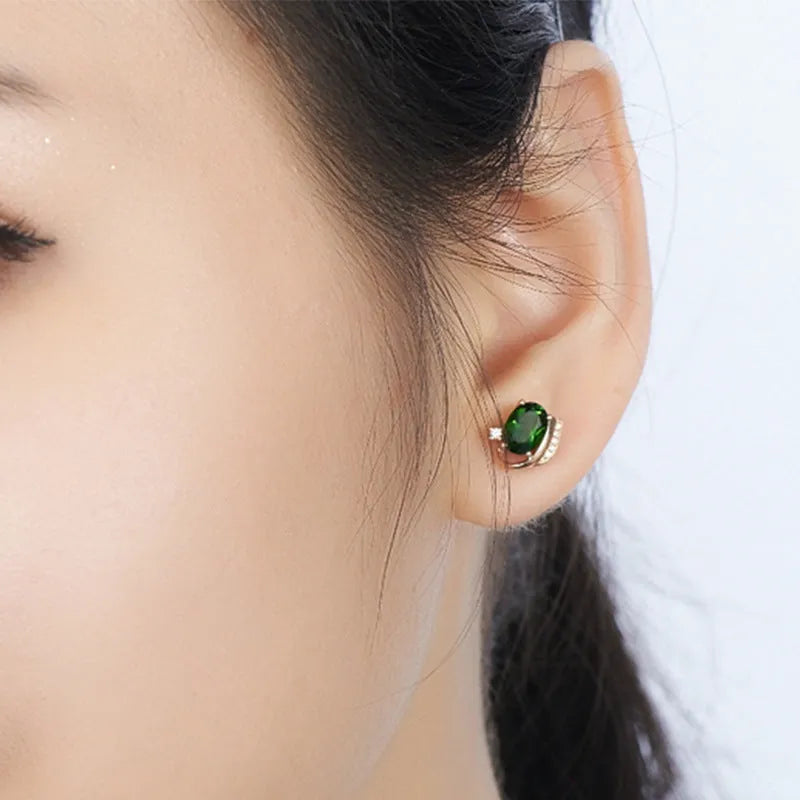 Pair of green ghost crystal stud earrings in silver with diamond-cut geometric shape on white background