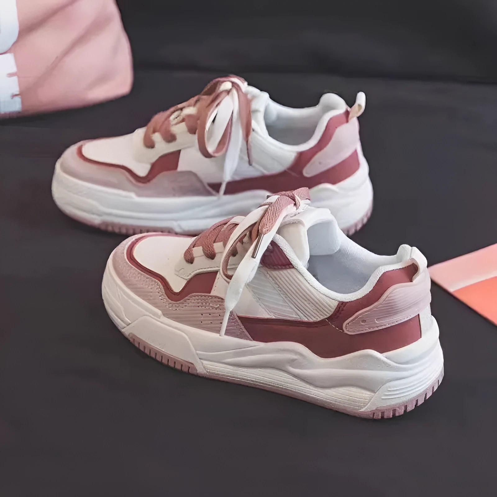 Pink and white low-top spring sneakers with rubber sole on a plain background