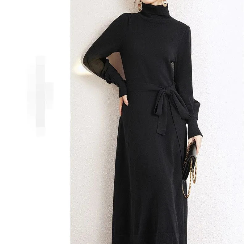 A woman wearing a rose red turtleneck long sleeve knitted dress with an elastic waist and a loose mid-length skirt.