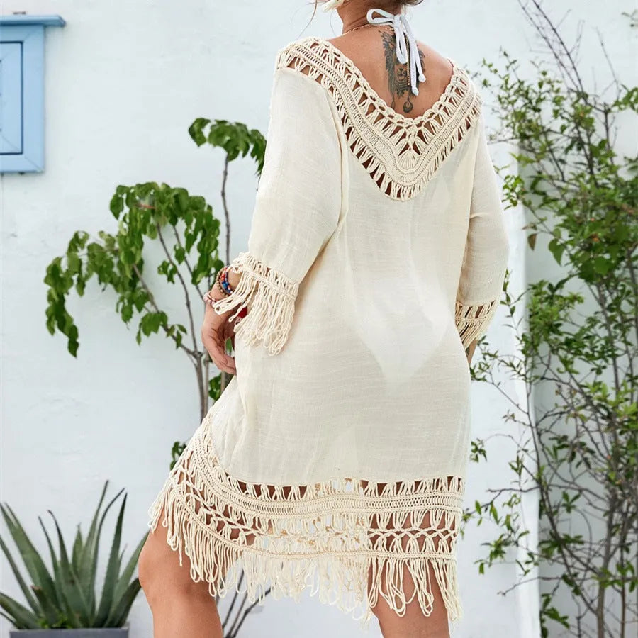 Apricot coloured crocheted patchwork beach dress on a hanger, showing mid-length skirt and half sleeves.
