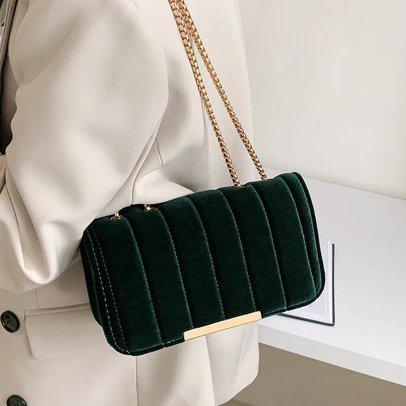 One shoulder velvet chain crossbody bag in solid colour, small square shape with gold chain strap, on white background.