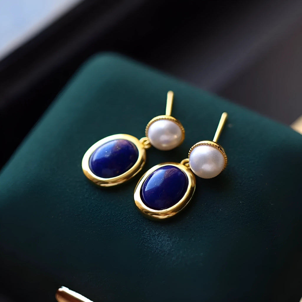A pair of simple silver earrings with blue lapis lazuli pearls and auspicious pattern details.