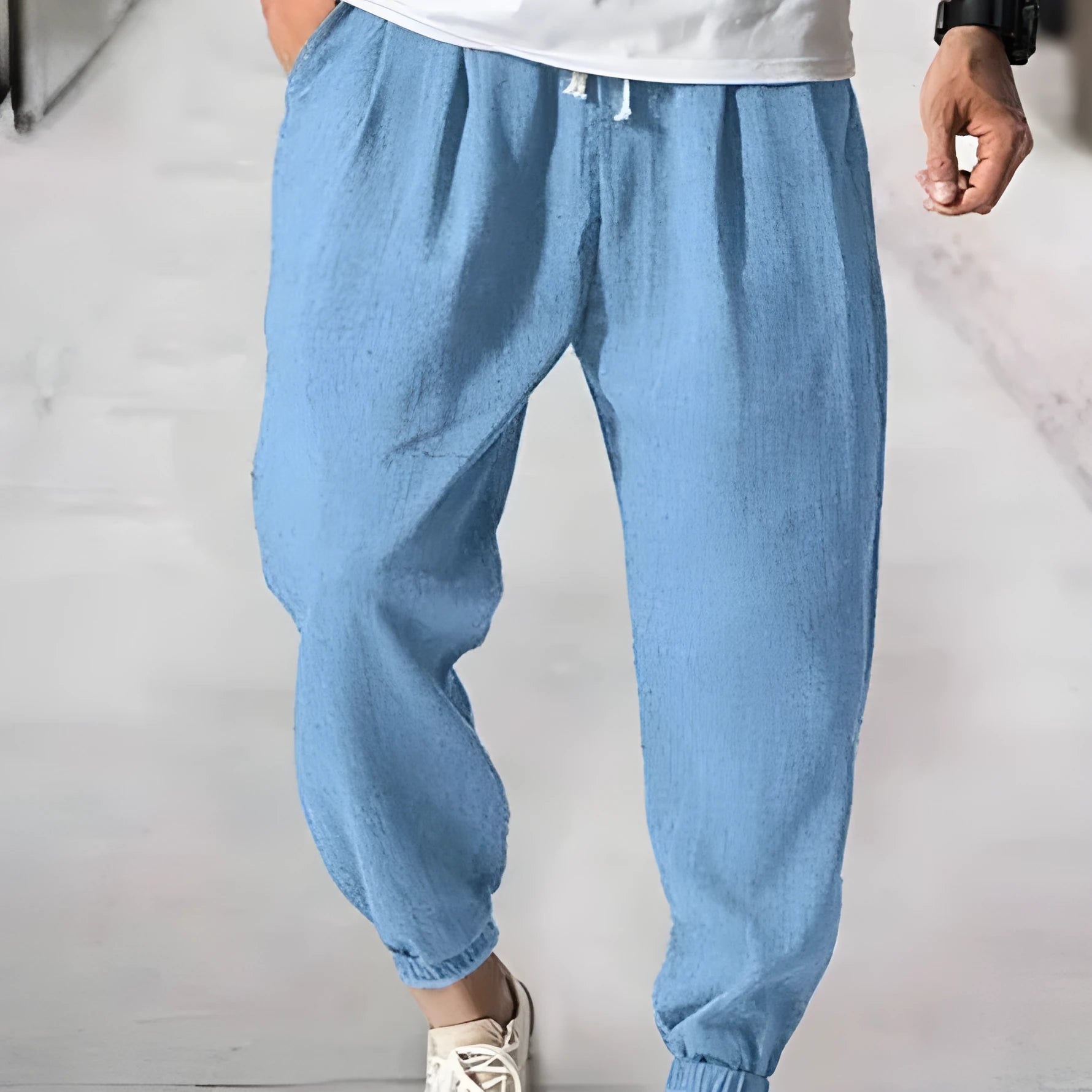 Man wearing loose light-coloured cotton trousers with elasticated ankle cuffs, showing front and side views.