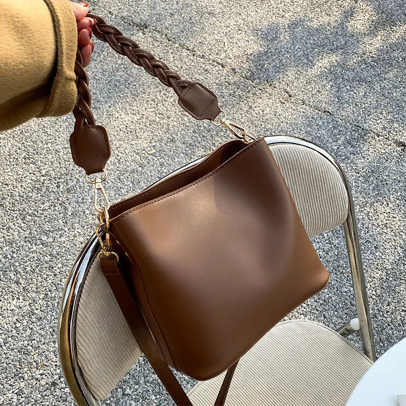 Retro woven PU leather crossbody bucket bag in an androgynous style.