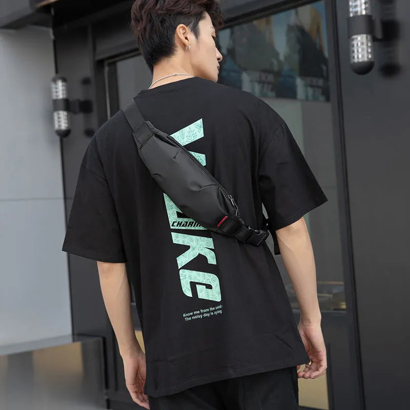 Black Oxford cloth men's crossbody waist pack showing front zipper and compact size.