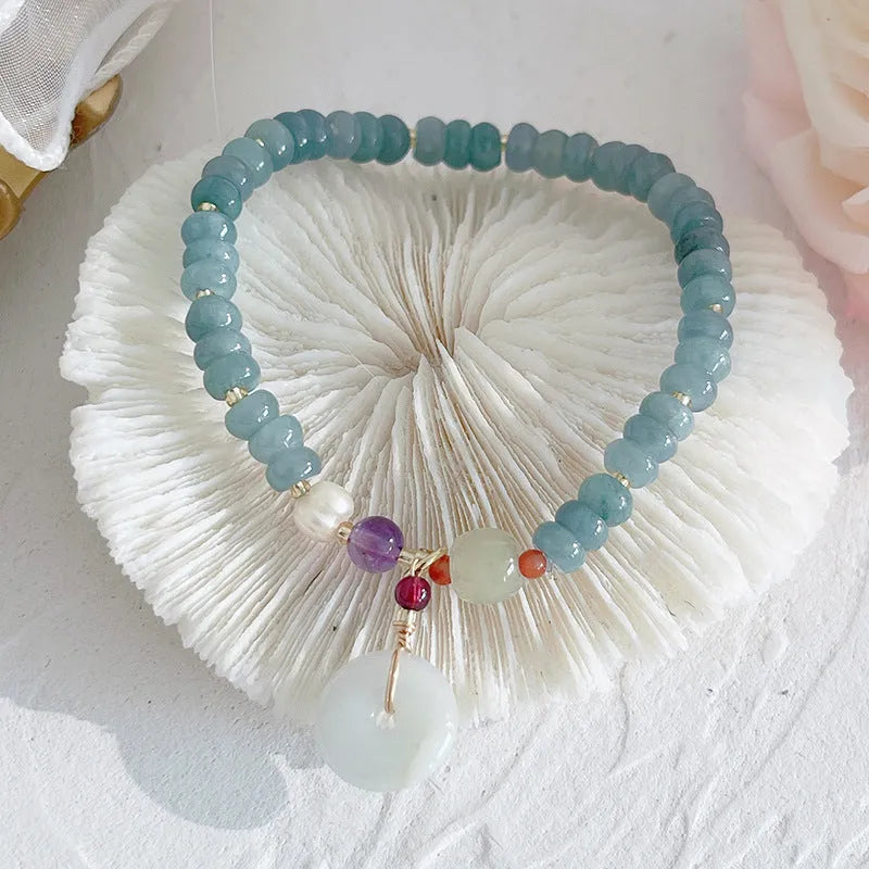 Blue-toned jade bracelet with gourd and peace buckle charms and strawberry quartz accents