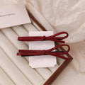 Wine red leather hair clip with a classic bow design on a white background.