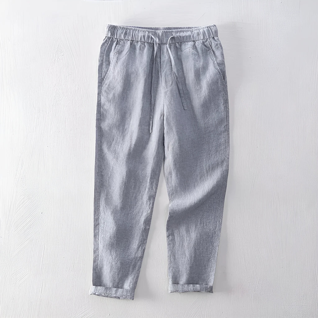 Men's straight-leg linen trousers in light grey, laid flat to show the mid-waist and tailored cut.