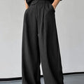 Men's black vertical striped pleated casual trousers showing elastic construction detail